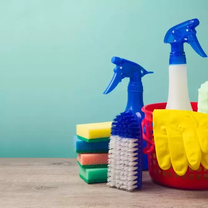A spray bottle of cleaner and other cleaning implements in a  basket ready for spring cleaning your apartment.