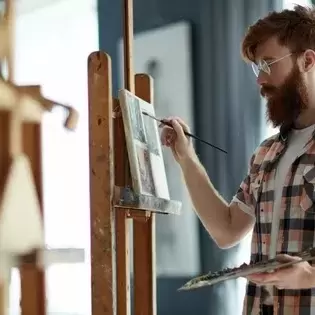 A man standing at an easel painting.